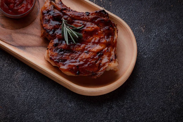 Karamelize soslu ızgara domuz bifteği. Çevre dostu ahşap kaplarda et servisi. Taze biberiye ve domates sosu..