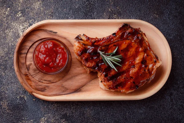 Karamelize soslu ızgara domuz bifteği. Çevre dostu ahşap kaplarda et servisi. Taze biberiye ve domates sosu..