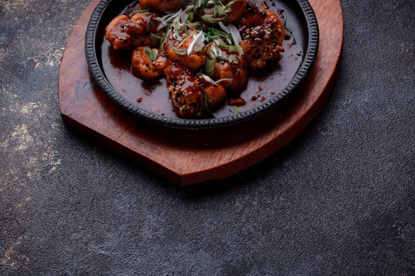 Kızarmış et ve karamelli soslu sıcak tava. Pişirilmiş ve garnitür olarak taze sebzeler. Keten tohumu ve susam tohumu eklenmiş bir yemek..