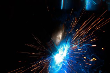 Arc welding. Welding pipes in inert gases. MIG / MAG. A bright flash of light and a sheaf of sparks.