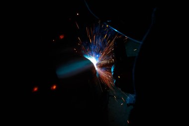 Kaynak yayı. Durağan gazlardaki kaynak boruları. MIG / MAG. Parlak bir ışık ve bir tutam kıvılcım..