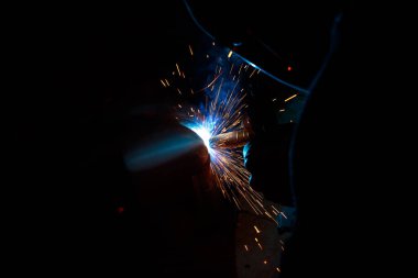 Kaynak yayı. Durağan gazlardaki kaynak boruları. MIG / MAG. Parlak bir ışık ve bir tutam kıvılcım..