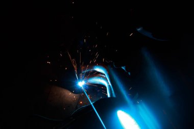 Kaynak yayı. Durağan gazlardaki kaynak boruları. MIG / MAG. Parlak bir ışık ve bir tutam kıvılcım..