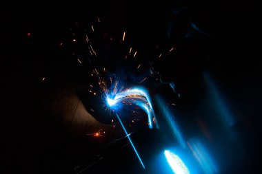 Kaynak yayı. Durağan gazlardaki kaynak boruları. MIG / MAG. Parlak bir ışık ve bir tutam kıvılcım..