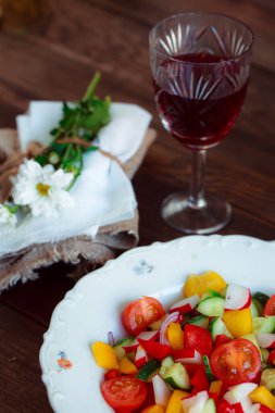 Bahar sebze salatası. Papatyalar, bir bardak şarap taze biber, otlar ve çatal bıçak takımı..