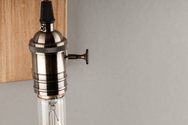 partial view of wooden wall lamp with Edison light bulb