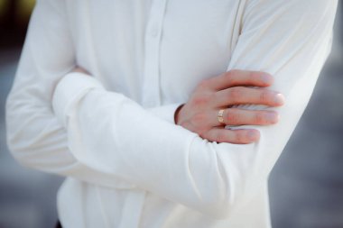 married man holding hands crossed on chest and wearing engaged ring 