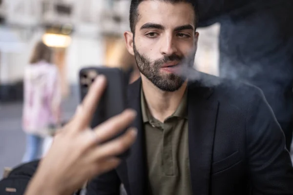 Trauriger Mann Der Zigarettenrauch Bläst Während Inhalte Auf Dem Handy — Stockfoto