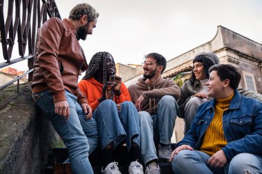 Multiracial best friends talking together sitting outdoors