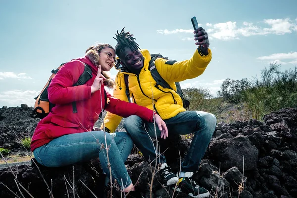 Kilku Młodych Turystów Siedzących Kamieniu Lawy Robiących Sobie Selfie Pomocą — Zdjęcie stockowe