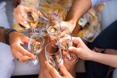 Birlikte kadeh kaldıran bir grup arkadaş - ellerindeki detaylar şampanya kadehleri - olay, doğum günü, yıldönümü veya kutlama yaşam tarzı konsepti - sol ele odaklan