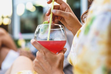 Portakal suyu kokteyli içen ve açık havada içki içen bir kadın eli. Alkol ve insanların yaşam tarzı. Ellerinde ekin aşısı var.