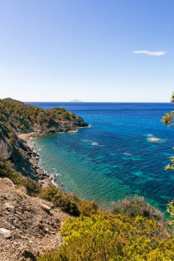 High angle view over Ogliera beach, a little wild free beach with dark sand, rocks and stones near Pomonte perfekt for snorkeling and deep sea diving to a shipwreck