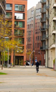 Almanya 'nın modern binalarıyla çevrili Hamburg sokaklarında bisiklet süren bir bisikletçi.