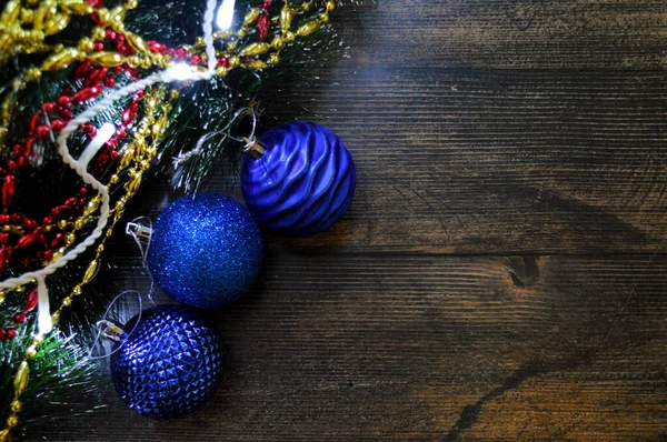 Köknar dalları, çelenkleri, hediyeleri ve mavi topları olan koyu renk ağaçların Noel arkaplanı. — Stok fotoğraf