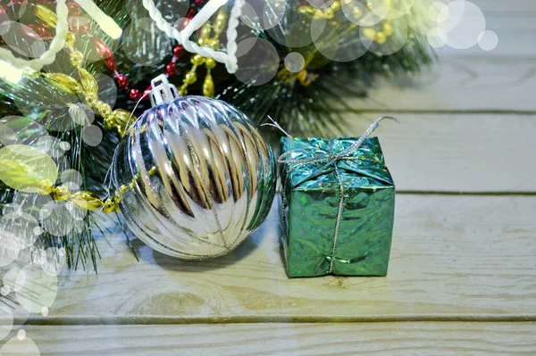 Background of wood with fir branches, garland, gift, ball, red and gold beads — Foto Stock