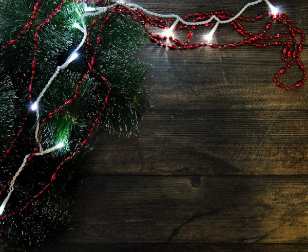 Vánoční zázemí z tmavého dřeva s jedlovými větvemi, věnci a červenými korálky — Stock fotografie