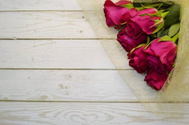 Kırmızı gül buketi beyaz ahşap arka planda yatıyor..
