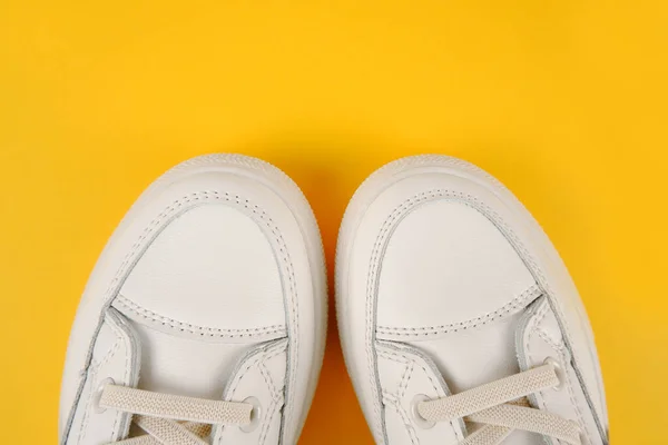 随意舒适的白色鞋子 时尚的女用皮鞋 鞋带黄色背景 季节性销售 鞋子折扣 对白皮肤的适当护理 — 图库照片