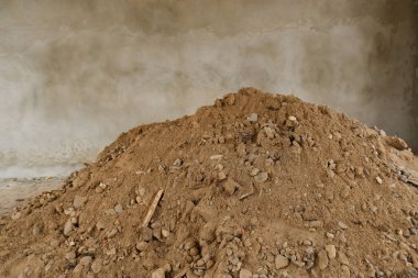 İnşaat sahasında duvara karşı kum ve çakıl yığını. İnşaat malzemeleri, tamirat, inşaat, yol inşaatı..