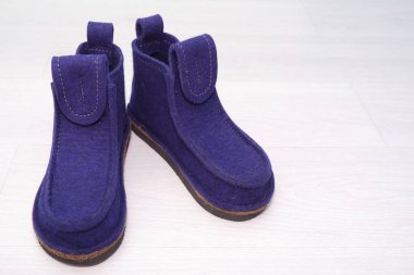 Modern stil keçeli botlar, gri ahşap arka planda mavi renkte keçelenk yünden yapılmış doğal botlar. Ülke için kuzey sıcak terlikleri. Valeshi.