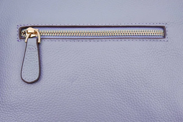 A steel zipper folded on the details or pocket of a blue-purple leather jacket or bag of 2022 as a background.The concept of shopping,a sewing workshop for sewing and repairing clothes and accessories.