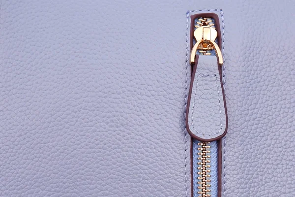Steel zipper on the side, folded on the details or pocket of a blue-purple leather jacket or bag 2022 as a background.The concept of a sewing workshop for sewing and repairing clothes and accessories