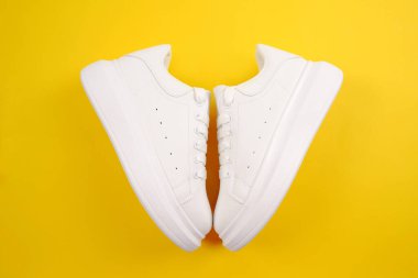 Rahat rahat beyaz ayakkabılar. Sarı arka planda bağcıkları olan yüksek bir platformda şık kadın deri ayakkabıları. Mevsimlik satışlar, promosyonlar, ayakkabı indirimleri. Beyaz ten için uygun bakım.