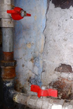 Eski püskü duvarların arka planında adaptör olan borular ve pirinç musluklar. Tesisat ve gaz tesisatının onarımı ve bağlantısı. Dikey fotoğraf. Kopyalama uzayı.