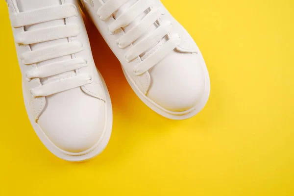 随意舒适的白色鞋子 时尚的女用皮鞋 鞋带黄色背景 季节性销售 鞋子折扣 对白色皮肤的适当护理 — 图库照片