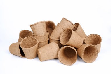 Beyaz arka planda fidanlar için bir sürü turba saksısı. Baharda tohum ekme, tarım ve kendi yiyeceğinizi yetiştirme kavramı.