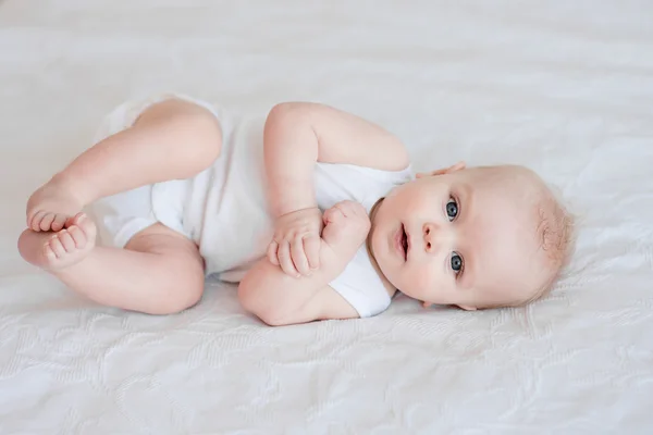 Portret van schattige babyjongen liggend op het bed op zijn kant — Stockfoto