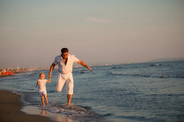 Happy father running with his daughter by the seaside at sunset, — Stock Photo, Image
