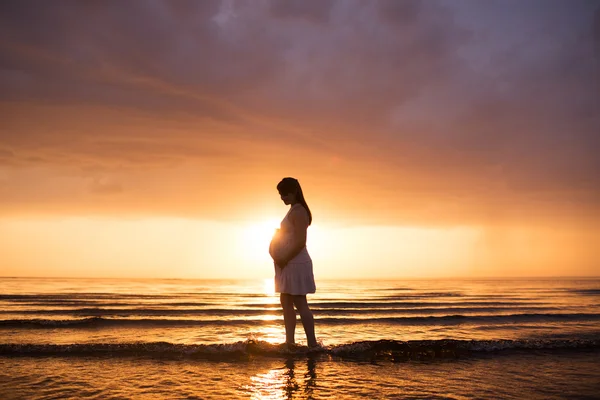 日没時の妊娠中の女性のシルエット ストック写真