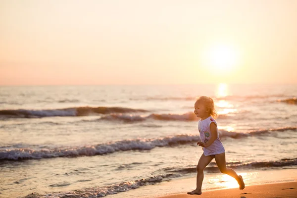 Glücklich schönes kleines Mädchen läuft am Strand bei Sonnenuntergang, Italien, Stockbild