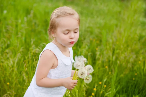 Gelukkig kind waait paardebloem buitenshuis in zomer park — Stockfoto