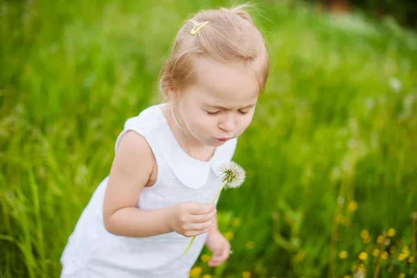 Gelukkig kind waait paardebloem buitenshuis in zomer park — Stockfoto