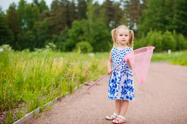 Meisje met vlinder net plezier op veld — Stockfoto