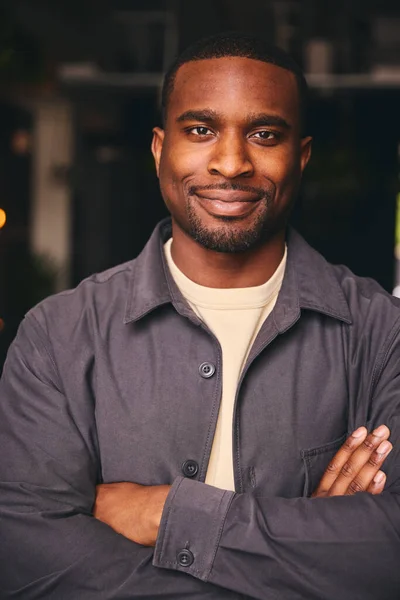 Smiling Young Black Male Standing In Office Looking At Camera With Arms Crossed