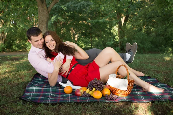 Hermosa pareja joven de picnic en el campo. Familia feliz al aire libre. Hombre y mujer sonrientes relajándose en Park. Relaciones entre Estados miembros — Foto de Stock