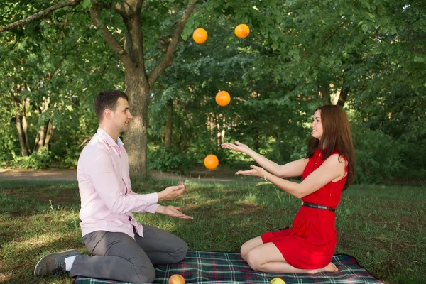 Krásný mladý pár s piknik v přírodě. venkovní šťastná rodina. usmívající se muž a žena relaxační v parku. vztahy — Stock fotografie