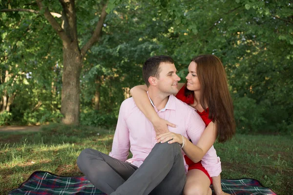 Krásný mladý pár s piknik v přírodě. venkovní šťastná rodina. usmívající se muž a žena relaxační v parku. vztahy — Stock fotografie