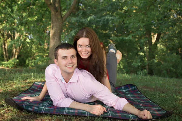 Hermosa pareja joven de picnic en el campo. Familia feliz al aire libre. Hombre y mujer sonrientes relajándose en Park. Relaciones entre Estados miembros — Foto de Stock