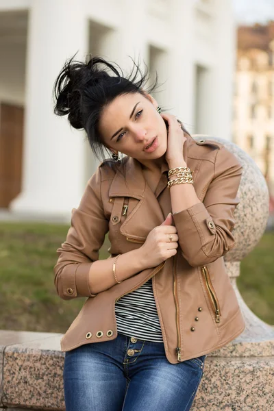 Sexy Girl in leather dress sitting on a bench in the park. — Stock Photo, Image