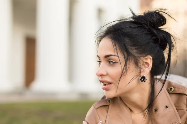 Menina sexy em vestido de couro sentado em um banco no parque . — Fotografia de Stock