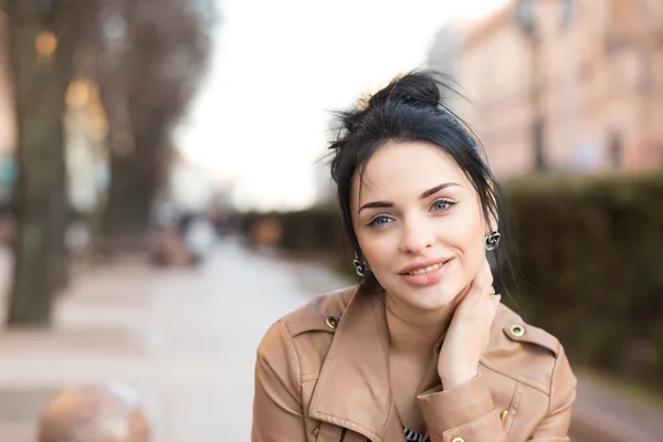 Sexy Mädchen im Lederkleid sitzt auf einer Bank im Park. — Stockfoto