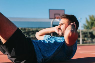 Genç bir adam dışarıda karın kaslarını çalıştırıyor. Üstesinden gelme, çaba, ödül, fedakarlık ve başarı kavramı..