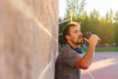Erkek sporcu, gün batımında dışarıda yaptığı sıkı çalışmadan sonra alkol, bkaa, kreatin, kazein veya enerji içeceği alır. Sağlık, beslenme, sağlık hizmetleri kavramı.