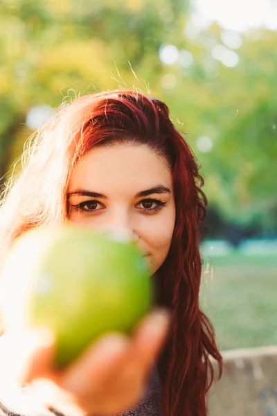 Pionowy Obraz Pięknej Młodej Rudej Kobiety Trzymającej Zielone Jabłko Zewnątrz — Zdjęcie stockowe