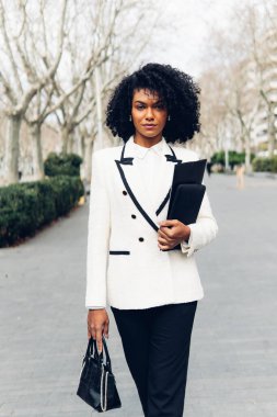 Kendine güvenen bir iş kadınının dikey görüntüsü. Dosyasıyla ve çantasıyla dümdüz yürüyor..